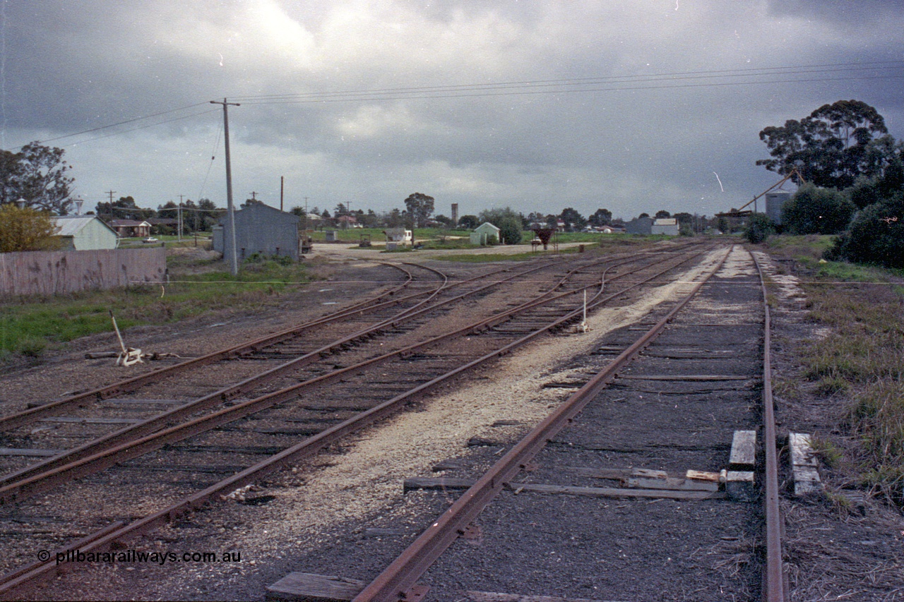 103-17
Wahgunyah station yard overview, super phosphate sheds on the left track, portable station building in middle of frame, silos in distance, scotch block and point levers in foreground.
