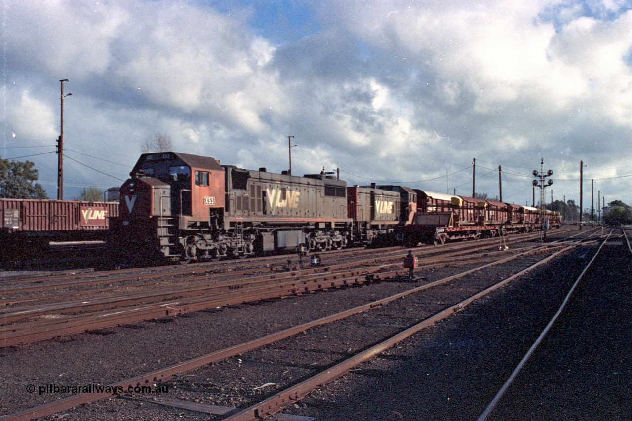 103-27
Benalla station yard overview, V/Line broad gauge stabled down Wodonga goods train 9303, locomotives V/Line X class loco X 53 with serial 75-800 a Clyde Engineering Rosewater SA built EMD model G26C and T class T 403 Clyde Engineering EMD model G18B serial 67-498, rail recovery rake beside stabled train, ground dwarf and disc signal posts, yard still intact.
Keywords: X-class;X53;Clyde-Engineering-Rosewater-SA;EMD;G26C;75-800;