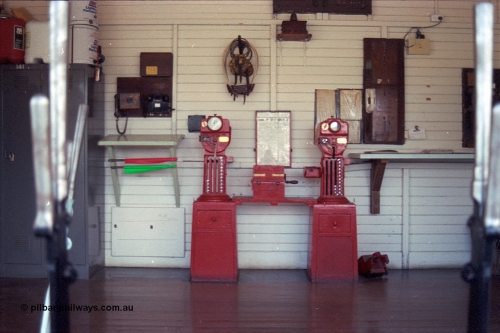 104-15
Buangor, view inside signal box through window, miniature electric staff exchange machines, Buangor to Ararat machine on the left and Trawalla to Buangor machine on the right, control telephones, chart of bell codes, tins of kerosene, exchange hoops and other paraphernalia for running trains in the 19th century.
