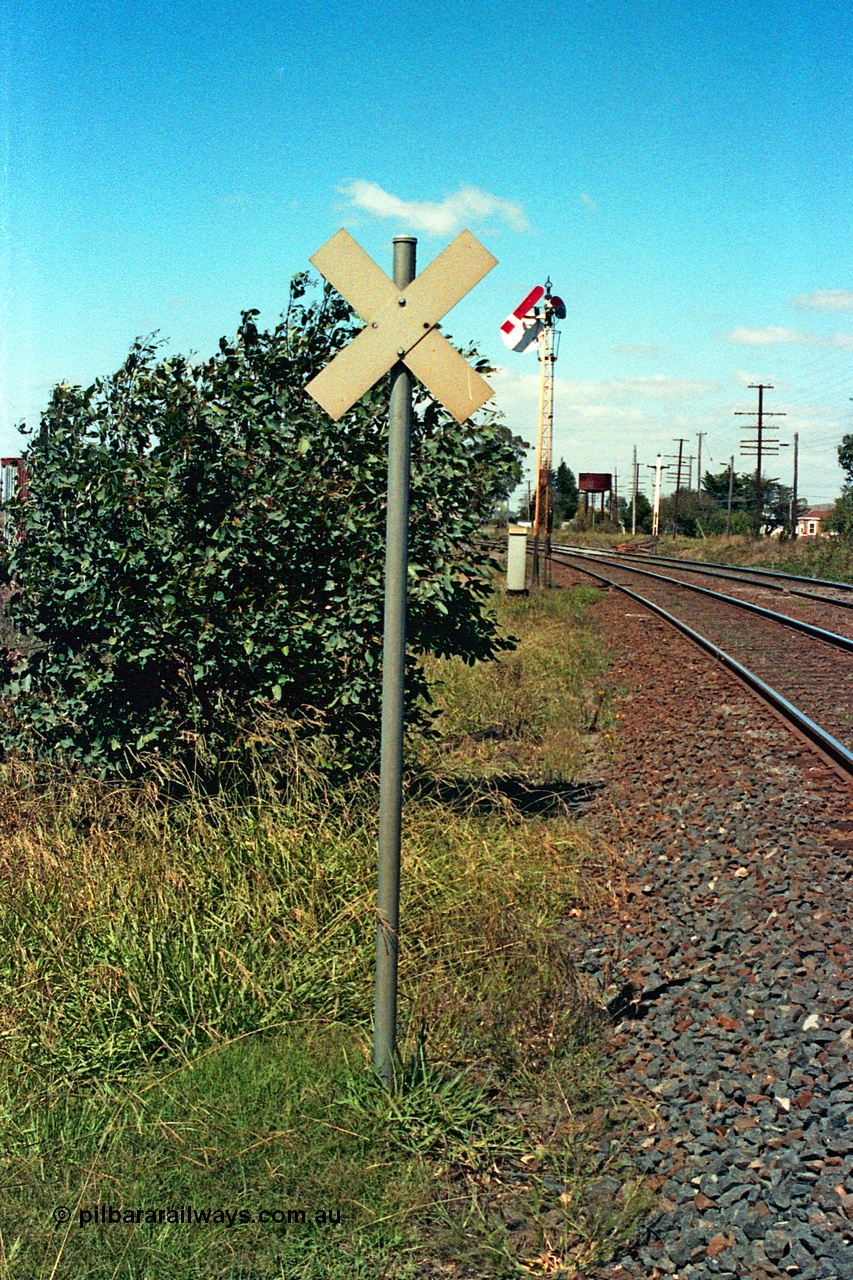 105-24
Wallan, level crossing indicator on up mainline, semaphore signal post 16 with sighting disc behind arm pulled off for up train, twin disc signal post 15 has been stripped, water tank in background, looking south.
