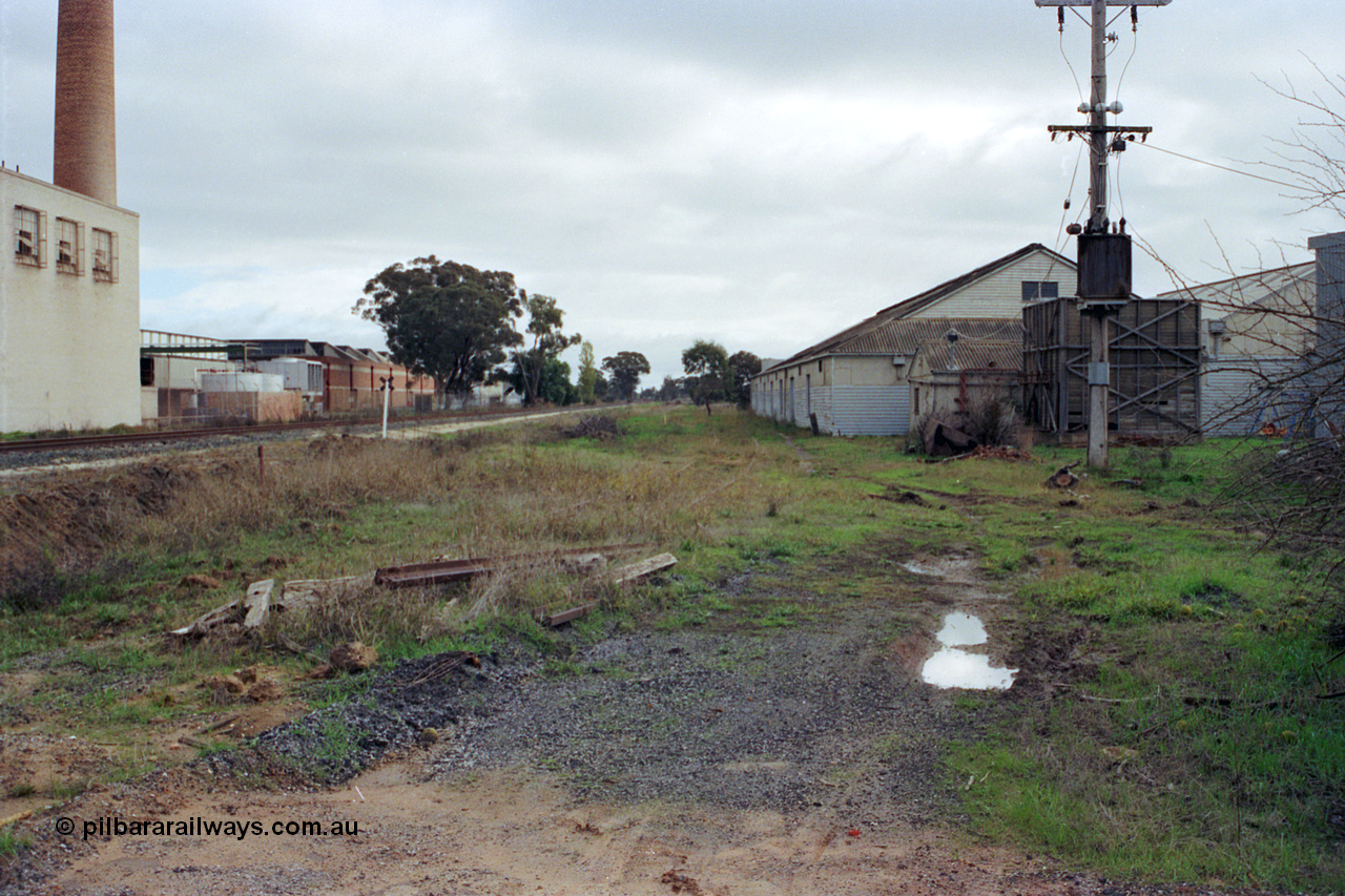 107-04
Kyabram track view, buried rails for Kyabram Fruit Packers siding, Southern Can Company on the left, looking towards Echuca.
