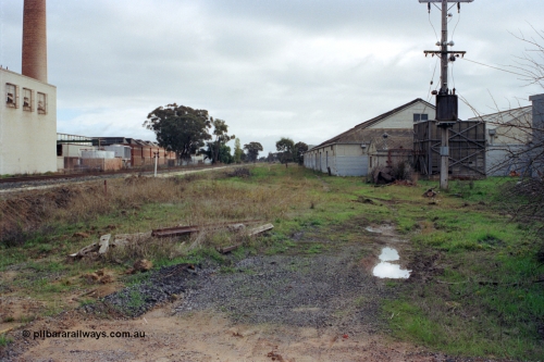 107-04
Kyabram track view, buried rails for Kyabram Fruit Packers siding, Southern Can Company on the left, looking towards Echuca.
