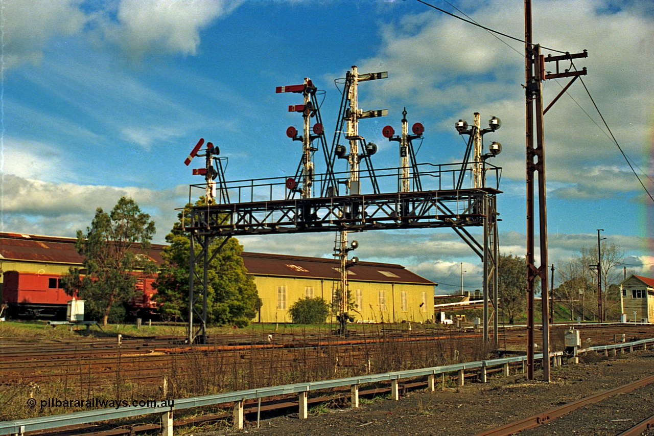 110-12
Benalla, the impressive signal gantry still intact in this view from 14th July 1991, only a couple of weeks later it was partially stripped of discs and semaphores, semaphore signal post 28 is pulled off for an up Albury passenger train, workshops behind and B signal box just visible on the right.
