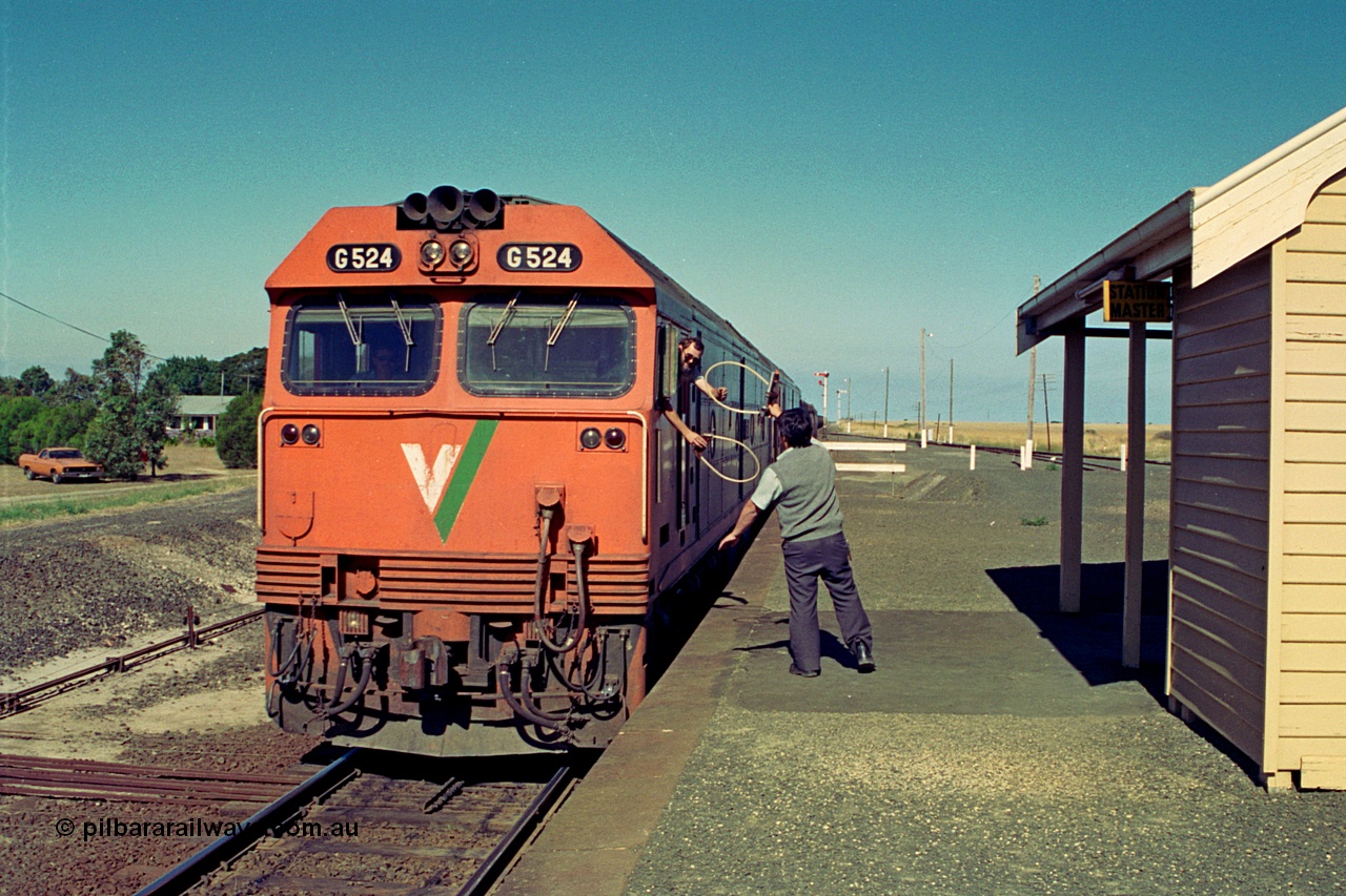 111-00
Gheringhap station platform view, safeworking, electric staff exchange with V/Line broad gauge down grain train 9125 behind G class locos G 524 Clyde Engineering EMD model JT26C-2SS serial 86-1237 and G 528, driver swaps the electric staves with the signaller to continue towards Ballarat.
Keywords: G-class;G524;Clyde-Engineering-Rosewater-SA;EMD;JT26C-2SS;86-1237;