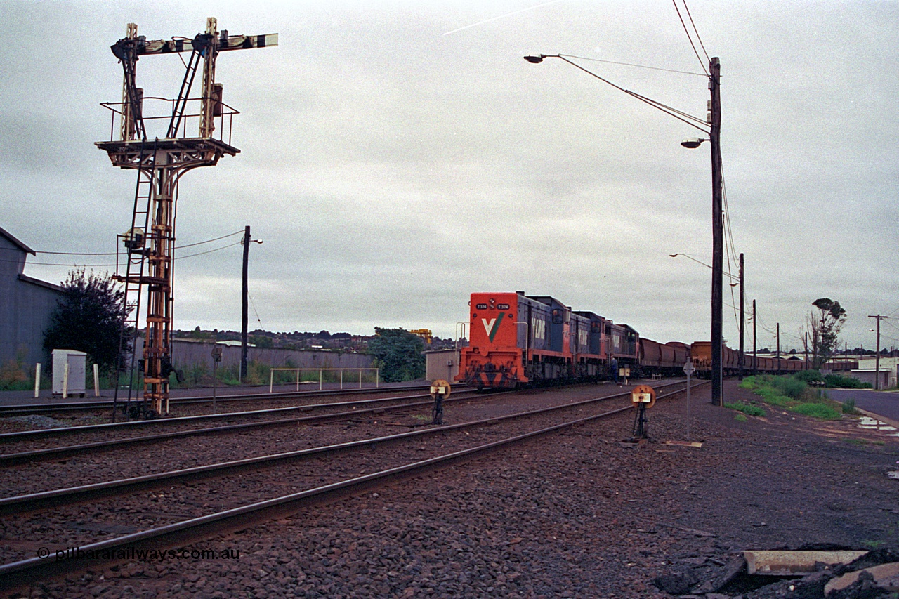 111-05
North Geelong grain arrivals yard, V/Line broad gauge locos T class T 374 Clyde Engineering EMD model G8B serial 64-329, T class 3?? and X class X 42 Clyde Engineering EMD model G26C serial 70-705 arrive with the up Mt Gambier goods train 9192, semaphore signal post 13 and ground dwarf disc signals 12 and 14 face away from the camera, loaded grain rake on the right.
Keywords: T-class;T374;Clyde-Engineering-Granville-NSW;EMD;G8B;64-329;