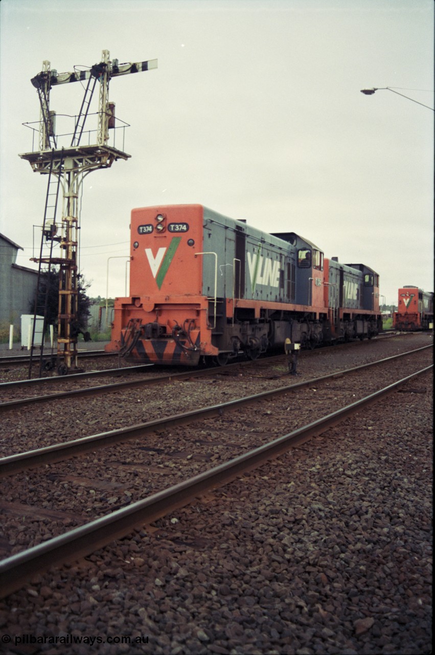 111-08
North Geelong grain arrivals yard, V/Line broad gauge locos T class T 374 Clyde Engineering EMD model G8B serial 64-329 and T class 3?? shunt past ground disc signal 12 pulled off for the move, under semaphore signal post 13, X class X 42 Clyde Engineering EMD model G26C serial 70-705 is still on the up Mt Gambier goods train 9192 at the far right.
Keywords: T-class;T374;Clyde-Engineering-Granville-NSW;EMD;G8B;64-329;