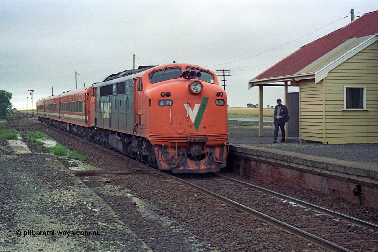 111-14
Gheringhap station view, V/Line broad gauge A class A 71 Clyde Engineering EMD model AAT22C-2R serial 83-1180 rebuilt from B 71 Clyde Engineering EMD model ML2 serial ML2-12 and N set work the down Ararat via Nth Geelong passenger train 8105, pausing to swap the electric staff for the ordinary train staff ticket to Warrenheip, signaller has the train staff to show the driver and the ticket which the driver will use as his authority to Warrenheip. This working of special train staff and ticket was introduced in November 1993 for the line between Gheringhap and Warrenheip on weekends only, replacing the electric staff section Gheringhap to Meredith.
Keywords: A-class;A71;Clyde-Engineering-Rosewater-SA;EMD;AAT22C-2R;83-1180;rebuild;bulldog;