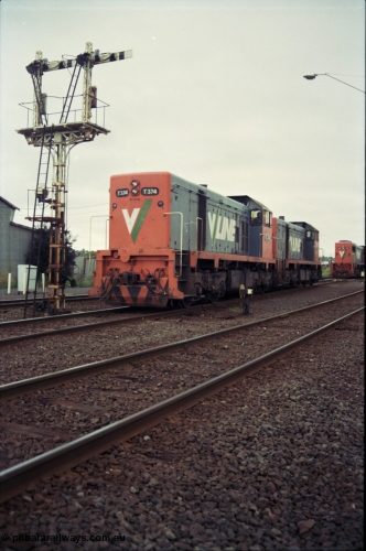 111-08
North Geelong grain arrivals yard, V/Line broad gauge locos T class T 374 Clyde Engineering EMD model G8B serial 64-329 and T class 3?? shunt past ground disc signal 12 pulled off for the move, under semaphore signal post 13, X class X 42 Clyde Engineering EMD model G26C serial 70-705 is still on the up Mt Gambier goods train 9192 at the far right.
Keywords: T-class;T374;Clyde-Engineering-Granville-NSW;EMD;G8B;64-329;
