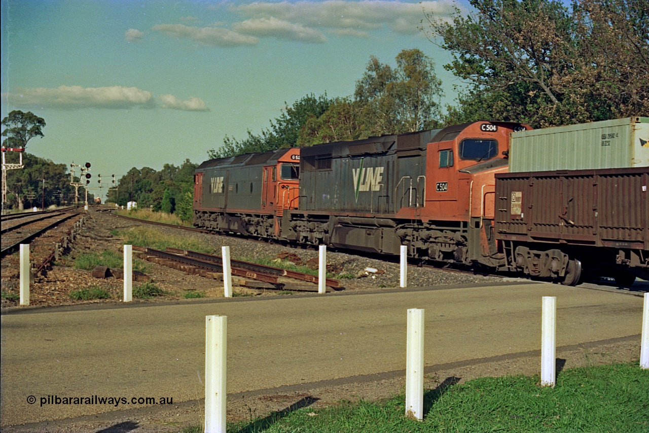 112-08
Violet Town, looking north across Cowslip Street, V/Line standard gauge down goods headed by G class G 529 Clyde Engineering EMD model JT26C-2SS serial 88-1259 and C class C 505 Clyde Engineering EMD model GT26C serial 76-828, trailing view, broad gauge lines at left, station building behind camera, 81 class on up goods holding the mainline in crossing loop in background, searchlight signals for standard gauge trains and semaphores for broad gauge, March 1994.
Keywords: G-class;G529;Clyde-Engineering-Somerton-Victoria;EMD;JT26C-2SS;88-1259;C-class;C505;GT26C;76-828;