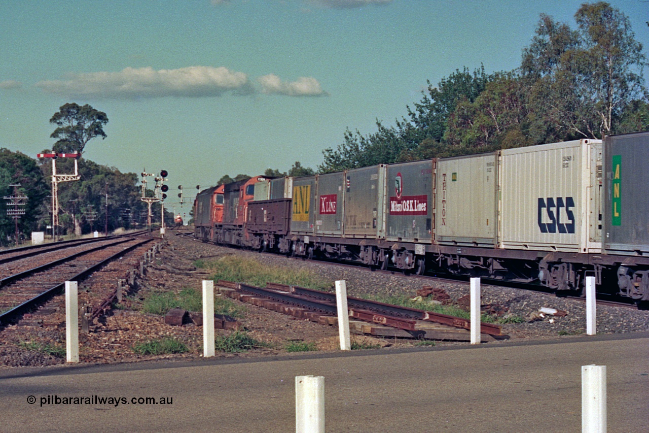 112-09
Violet Town, looking north across Cowslip Street, V/Line standard gauge down goods headed by G class G 529 Clyde Engineering EMD model JT26C-2SS serial 88-1259 and C class C 505 Clyde Engineering EMD model GT26C serial 76-828, trailing view, broad gauge lines at left, station building behind camera, 81 class on up goods holding the mainline in crossing loop in background, searchlight signals for standard gauge trains and semaphores for broad gauge, March 1994.
Keywords: G-class;G529;Clyde-Engineering-Somerton-Victoria;EMD;JT26C-2SS;88-1259;C-class;C505;GT26C;76-828;