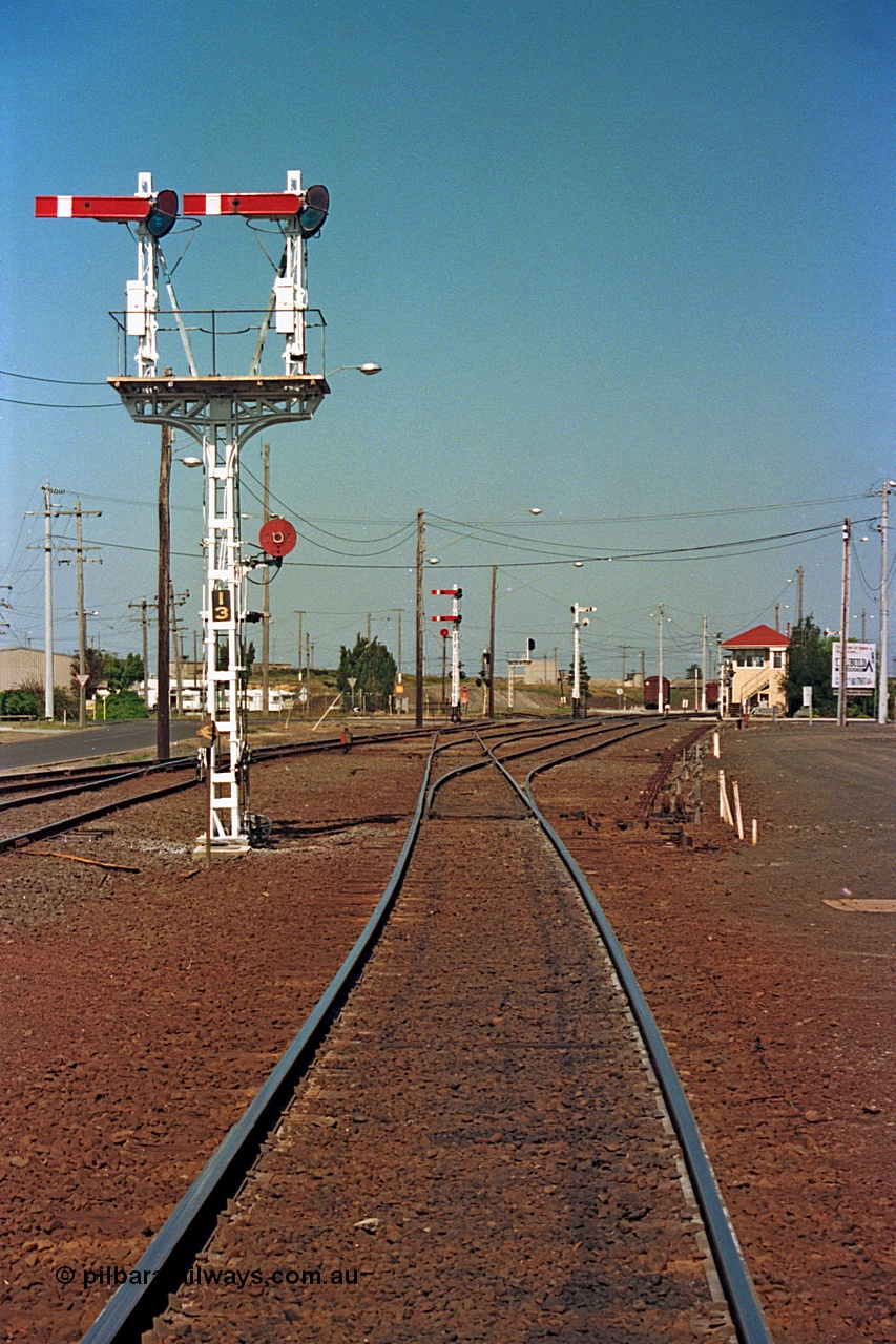 112-16
North Geelong yard overview, looking east, semaphore signal post 13 freshly repainted, signal posts 15 and 16 visible in the background, North Geelong C Box at right, standing on broad gauge mainline to Gheringhap, grain arrivals at left.
