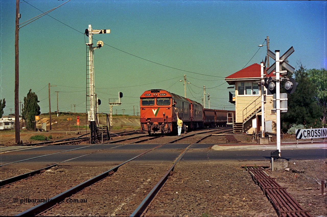 112-17
North Geelong C Box, Separation Street grade crossing, V/Line broad gauge grain train departing North Geelong Yard behind G classes G 534 Clyde Engineering EMD model JT26C-2SS serial 88-1264 and sister unit, signaller handing up electric staff for section to Gheringhap, ground dwarf signal 18 pulled off for departure, semaphores and searchlight signal posts, grade crossing, point rodding and signal box, safeworking.
Keywords: G-class;G534;Clyde-Engineering-Somerton-Victoria;EMD;JT26C-2SS;88-1264;