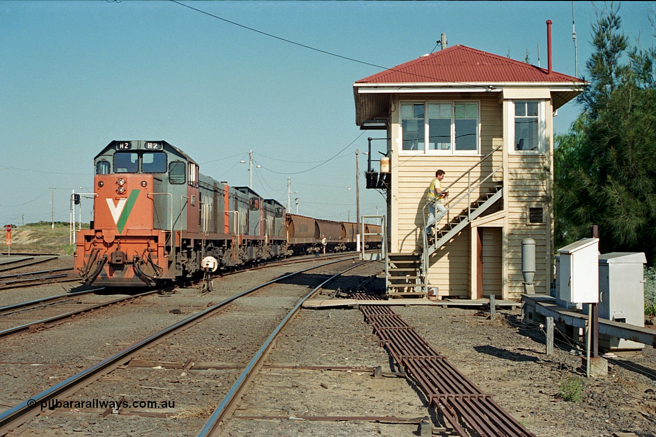 112-32
North Geelong C Box, V/Line broad gauge H class locos H 2 Clyde Engineering EMD model G18B serial 68-630, H 5 serial 68-632 and H 4 serial 68-633 shunt an empty grain train back into North Geelong yard past C Box, shunter in background, signaller returning to box, point rodding, ground dwarf signal.
Keywords: H-class;H2;Clyde-Engineering-Granville-NSW;EMD;G18B;68-630;H5;68-632;H4;68-633;