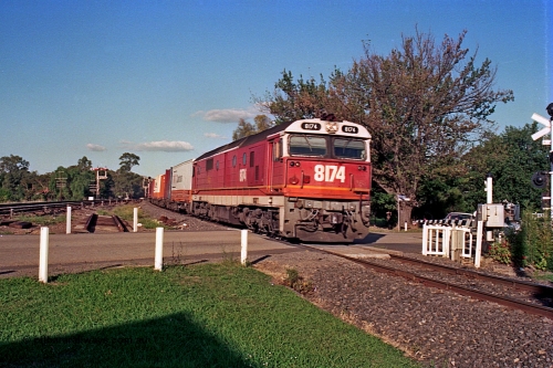 112-11
Violet Town, looking north across Cowslip Street, standard gauge NSWSRA 81 class 8174 Clyde Engineering EMD model JT26C-2SS serial 85-1093 in candy livery with an up goods heads south, station building behind camera, broad gauge track on the left, March 1994.
Keywords: 81-class;8174;Clyde-Engineering-Kelso-NSW;EMD;JT26C-2SS;85-1093;