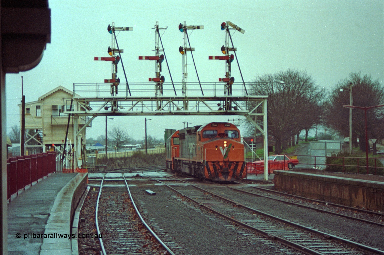 113-01
Ballarat station platform, Lydiard St signal box and signal gantry looking west from under station canopy, V/Line broad gauge up Adelaide goods train 9150 arrives behind C class C 506 Clyde Engineering EMD model GT26C serial 76-829 and G class G 538 Clyde Engineering EMD model JT26C-2SS serial 89-1271, in miserable conditions.
Keywords: C-class;C506;Clyde-Engineering-Rosewater-SA;EMD;GT26C;76-829;