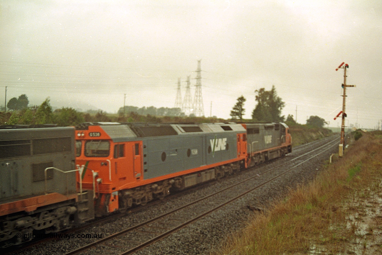 113-06
Warrenheip, up home semaphore signal post 11, V/Line broad gauge up Adelaide goods train 9150 grinds upgrade behind C class C 506 Clyde Engineering EMD model GT26C serial 76-829, G class G 538 Clyde Engineering EMD model JT26C-2SS serial 89-1271 and C class C 510 serial 76-833, in miserable conditions, poor quality off focus.
Keywords: G-class;G538;Clyde-Engineering-Somerton-Victoria;EMD;JT26C-2SS;89-1271;