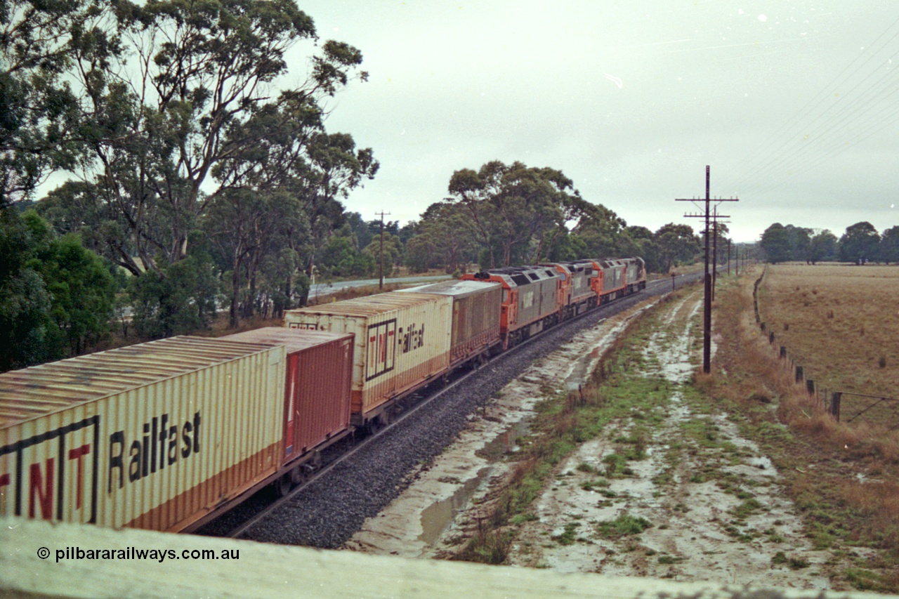 113-14
Near Gordon at Gascards Lane bridge, V/Line broad gauge up Adelaide goods train 9150 behind the quad CGCG combo of C class C 506 Clyde Engineering EMD model GT26C serial 76-829, G class G 538 Clyde Engineering EMD model JT26C-2SS serial 89-1271, C 510 serial 76-833 and G 513 serial 85-1241, in miserable conditions, poor quality, trailing view.
