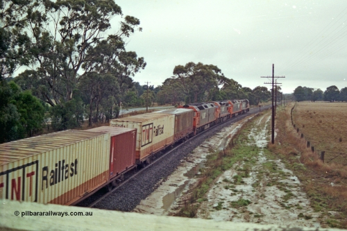 113-14
Near Gordon at Portland Flat road bridge, V/Line broad gauge up Adelaide goods train 9150 behind the quad CGCG combo of C class C 506 Clyde Engineering EMD model GT26C serial 76-829, G class G 538 Clyde Engineering EMD model JT26C-2SS serial 89-1271, C 510 serial 76-833 and G 513 serial 85-1241, in miserable conditions, poor quality, trailing view.
