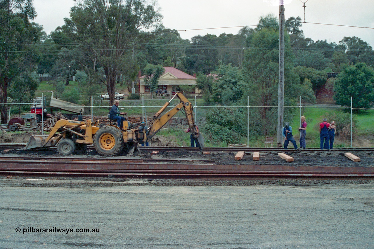 115-08
Hurstbridge, stabling sidings being upgraded, new sleepers being laid, John Deere backhoe and workers, Main Street in the elevated background.
