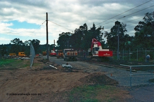 115-03
Hurstbridge, old stabling sidings being removed to make new stabling yard, new fencing, timber traction poles, crib crossing at right, Sumitomo excavator and workers.

