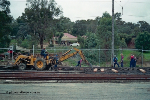 115-09
Hurstbridge, stabling sidings being upgraded, new sleepers being laid, John Deere backhoe and workers, Main Street in the elevated background.
