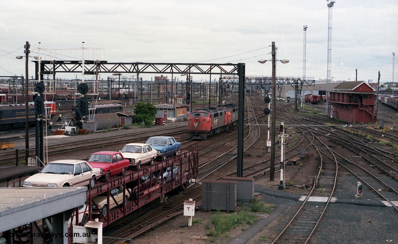 116-06
Spencer Street Station, view looking west from flyover, V/Line broad gauge A class light engines A 81 and A 62 run towards platform No.3, 'The Overland' Motorail waggons on platform No.2, DERMs 55 RM and 54 RM at left, West Tower in the middle background, Spencer Street No.1 Signal Box at right with broad gauge passenger stabling and maintenance sidings behind it, track work, points, searchlight signals and gantries and shunting signals.
