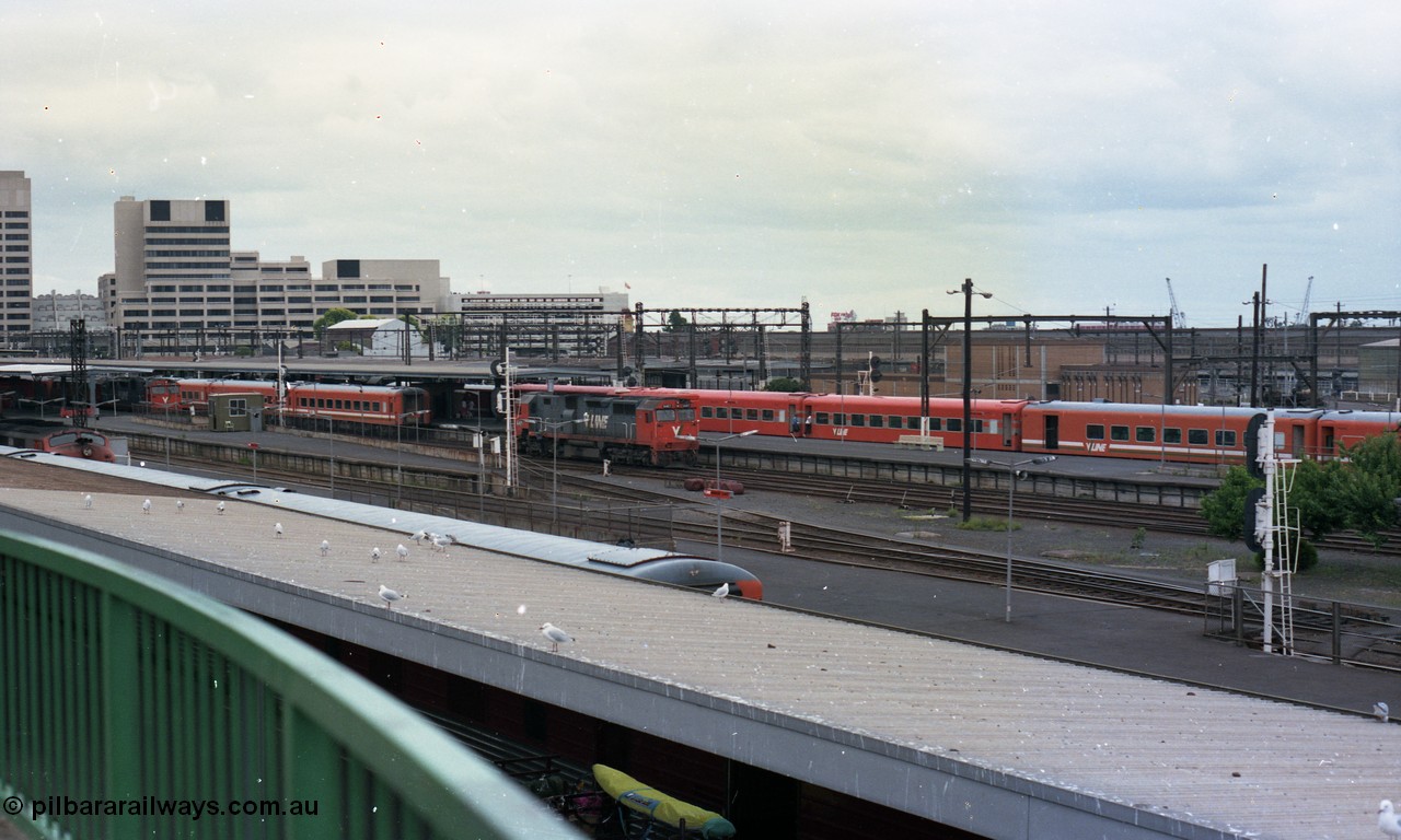 116-12
Spencer Street Station, view looking south from flyover, V/Line broad gauge passenger platforms, N class N 457 'City of Mildura' Clyde Engineering EMD model JT22HC-2 serial 85-1225 shunts away from an N set, behind it is a Victorian Railways 'Tea Cup' with V/Line liveried N set coupled to current V/Line liveried N set.
Keywords: N-class;N457;Clyde-Engineering-Somerton-Victoria;EMD;JT22HC-2;85-1225;