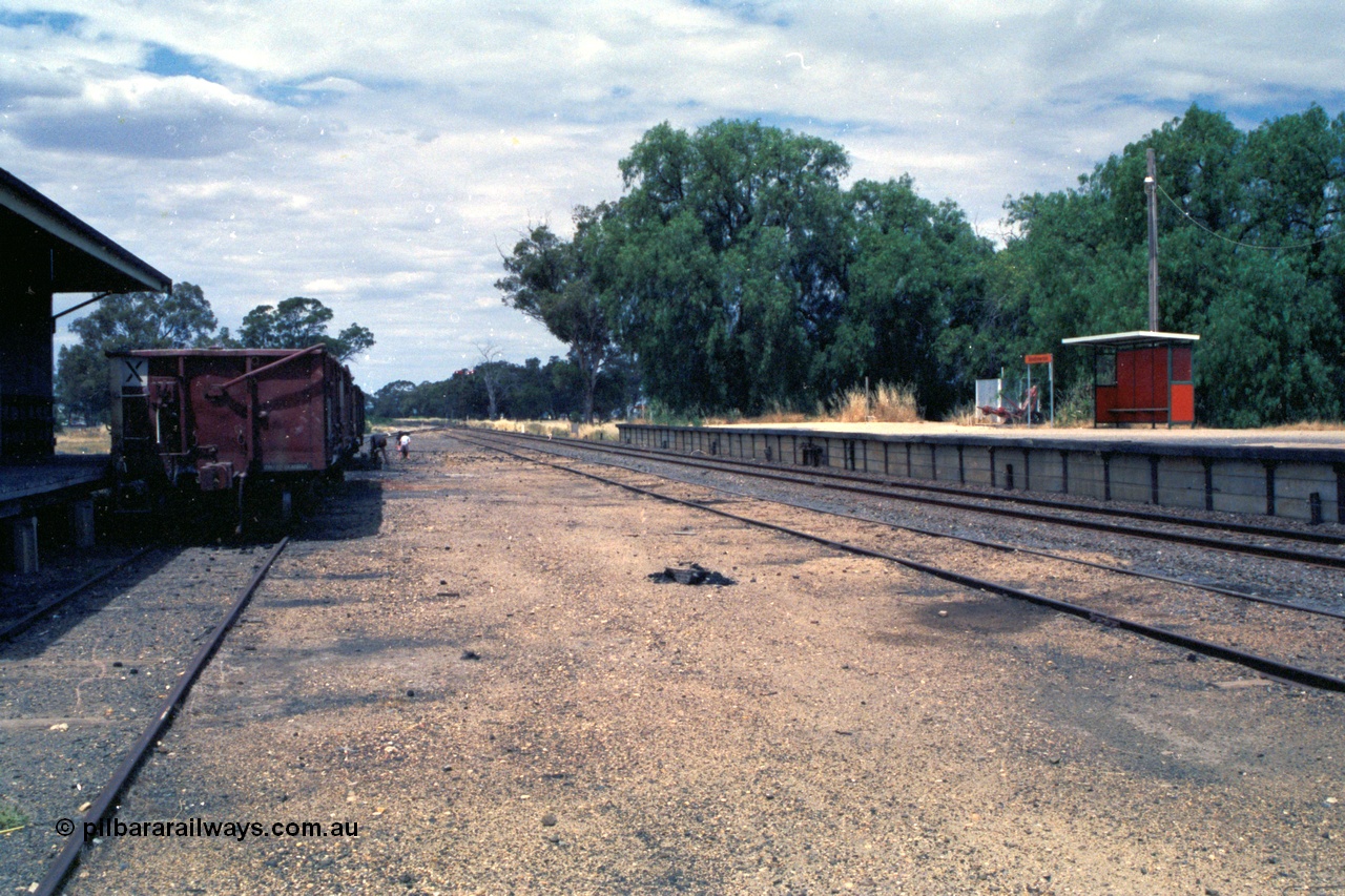 118-04
Strathmerton station yard overview, looking north, platform, bus style waiting shelter, signal bay, people picking coal, V/Line broad gauge VOBX type bogie open waggons.
Keywords: VOBX-type;