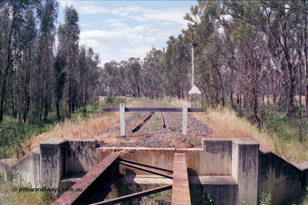 118-14
Tocumwal line, looking north from bridge in shot 118-13 towards Tocumwal, original down home signal mast and location landmark sign, 15 km/h sign in background and roof of original bridge cabin visible, line out of service. [url=https://goo.gl/maps/1dkdrejaR3NXRLjM6]Geo data[/url].
