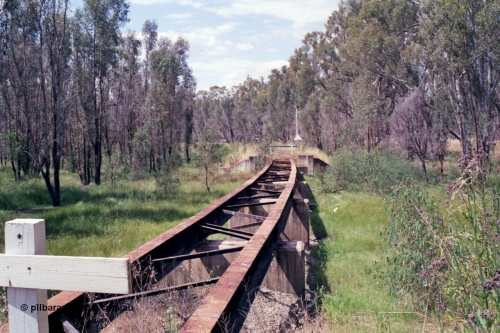 118-16
Tocumwal line, view of bridge looking north towards Tocumwal, down home signal mast and location board visible on far side of bridge, line out of service. [url=https://goo.gl/maps/Hvzxa15CUzFiCYKL6]Geo data[/url].
