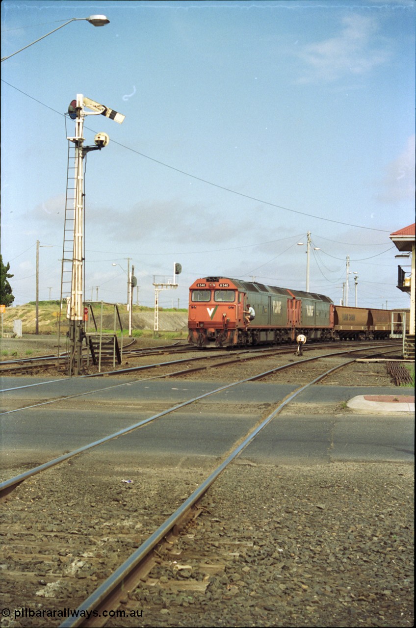 119-11
North Geelong C Box, V/Line broad gauge G classes G 540 Clyde Engineering EMD model JT26C-2SS serial 89-1273 and sister depart with down empty grain train 9125, looking across Separation Street, semaphore signal post 16 is pulled off for move, grade crossing, 2nd person climbing aboard with staff.
Keywords: G-class;G540;Clyde-Engineering-Somerton-Victoria;EMD;JT26C-2SS;89-1273;