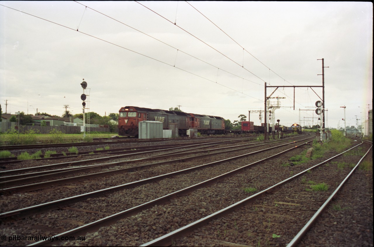 119-16
Sunshine, looking towards Tottenham, broad gauge down goods train 9149 is passed by down standard gauge goods train, V/Line G class locos, looking across all tracks.
