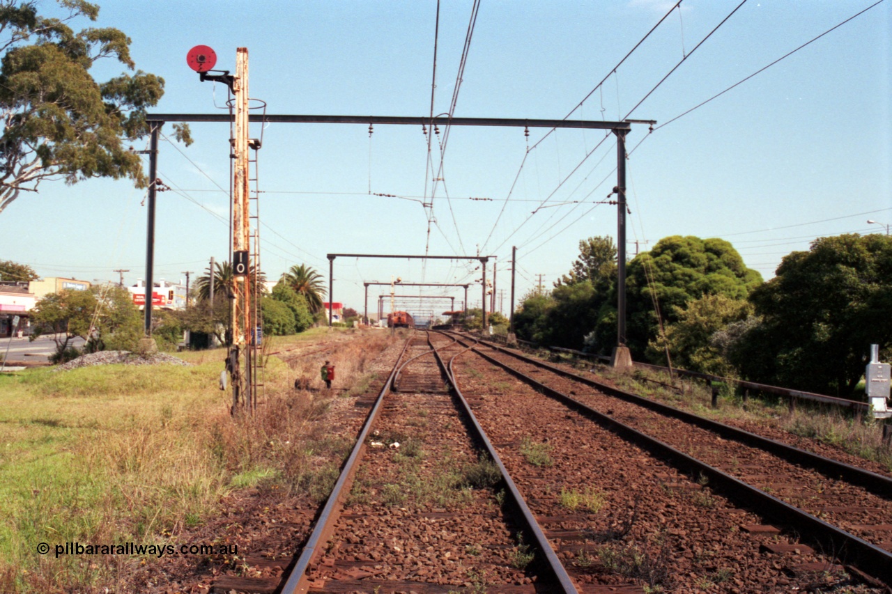 121-30
Morwell station yard overview looking from SEC or Briquette sidings road, signal Post 10, track at right is mainline to Traralgon, RT class rail tractor and station building in background.
