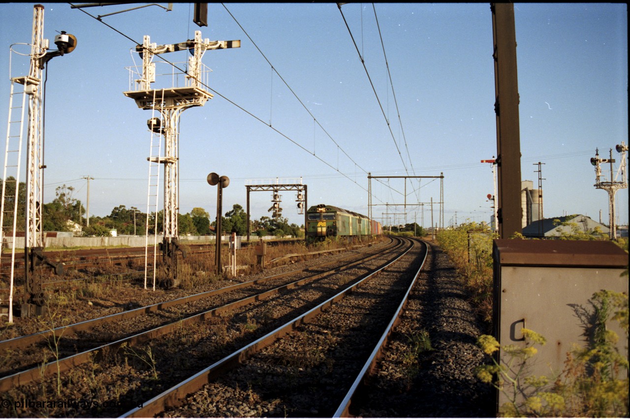 124-15
Sunshine looking from the passenger lines across to the Independent Through Goods lines, signal post 71 at camera, disc and semaphore signal posts 31 and 31B for control of the Independent Trough Goods lines, down Adelaide broad gauge goods train waiting to cross over the passenger lines, BL classes BL 30 Clyde Engineering EMD model JT26C-2SS serial 83-1014 and BL 35 Clyde Engineering EMD model JT26C-2SS serial 83-1019 in AN livery, standard gauge Sunshine Loop to the left of train, Newport Loop Line and GEB sidings at far right
