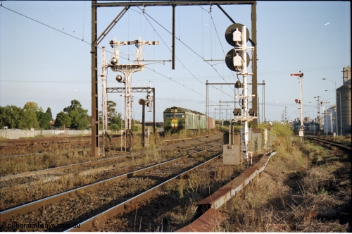 124-16
Sunshine looking from the passenger lines across to the Independent Through Goods lines, disc and semaphore signal posts 31 and 31B for control of the Independent Trough Goods lines, down Adelaide broad gauge goods train waiting to cross over the passenger lines, BL classes Clyde Engineering EMD model JT26C-2SS serial 83-1014 and BL 35 Clyde Engineering EMD model JT26C-2SS serial 83-1019 in AN livery, standard gauge Sunshine Loop to the left of train.
