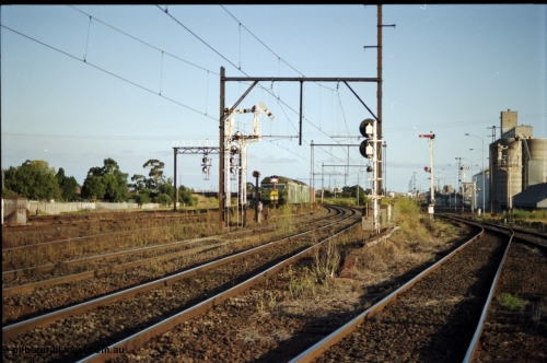 124-18
Sunshine looking from the passenger lines across to the Independent Through Goods lines, signal post 71 at camera, disc and semaphore signal posts 31 and 31B for control of the Independent Trough Goods lines, 31B pulled off for down Adelaide broad gauge goods train to cross over the passenger lines, BL classes Clyde Engineering EMD model JT26C-2SS serial 83-1014 and BL 35 Clyde Engineering EMD model JT26C-2SS serial 83-1019 in AN livery, standard gauge Sunshine Loop to the left of train, Newport Loop Line and GEB sidings at far right.
Keywords: BL-class;BL30;Clyde-Engineering-Rosewater-SA;EMD;JT26C-2SS;83-1014;