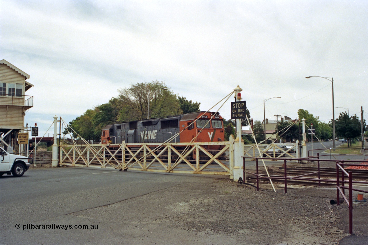 128-16
Ballarat Station, Lydiard St or B signal box, view across Lydiard Street grade crossing with interlocked gates closed, V/Line broad gauge N class N 464 'City of Geelong' Clyde Engineering EMD model JT22HC-2 serial 86-1193 shunts back along No.2 Rd crossing Lydiard Street.
Keywords: N-class;N464;Clyde-Engineering-Somerton-Victoria;EMD;JT22HC-2;86-1193;