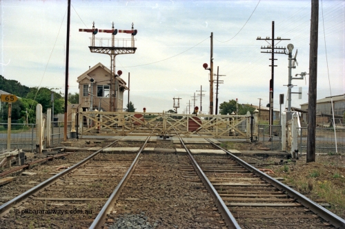 128-05
Ballarat, Linton Junction or Ballarat D signal box, looking west, gates about to be replaced with booms, semaphore triple doll signal Post 20 with disc for Timken's Siding, the three dolls are Cattle Yard Line, Linton Line and Ararat Line, and disc signal Post 21 for Timken's Siding, semaphore signal Post 23 in the distance, the 'ships wheel' in the signal box window is for operating the interlocked gates.
