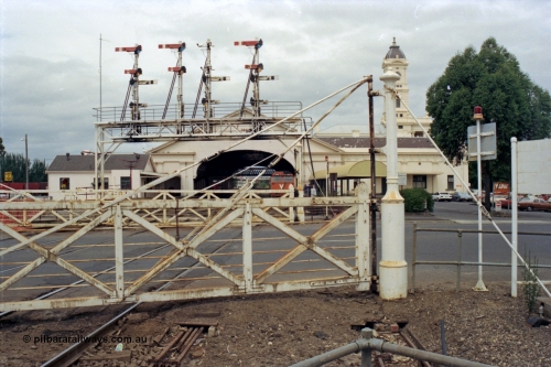 128-13
Ballarat Station, Lydiard St or B signal box, view across Lydiard Street grade crossing, interlocked gates, signal gantry with semaphore signal posts 26 to 29, looking east, V/Line N class N 464 'City of Geelong' Clyde Engineering EMD model JT22HC-2 serial 86-1193 at station, station building and canopy, point rodding under road.
Keywords: N-class;N464;Clyde-Engineering-Somerton-Victoria;EMD;JT22HC-2;86-1193;