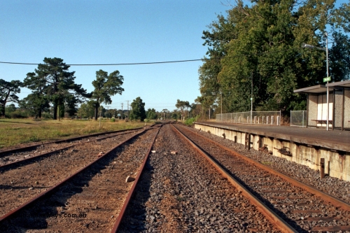 129-1-17
Baxter, station yard overview, looking towards Somerville, station platform and bus type concrete shelter, signal wires visible exiting platform coping, off focus.
