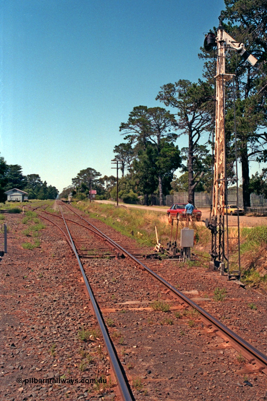 129-2-07
Lang Lang station yard overview, looking in the down direction towards Nyora from Melbourne end of yard, points and points and signal levers with interlocking, semaphore signal post, goods shed and station in the background.
