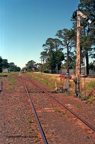 129-2-07
Lang Lang station yard overview, looking in the down direction towards Nyora from Melbourne end of yard, points and points and signal levers with interlocking, semaphore signal post, goods shed and station in the background.

