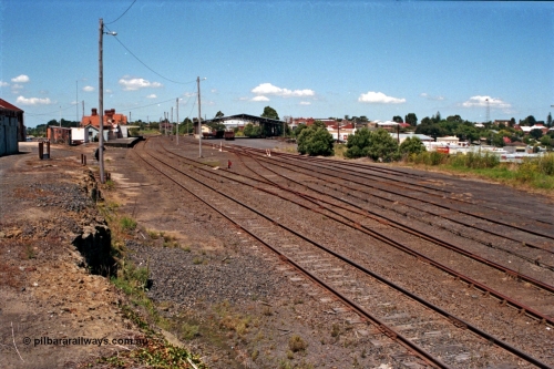 129-2-21
Korumburra station yard overview looking down direction, shows former Works Depot siding removed from alongside embankment, Freightgate canopy and overview of yard.
