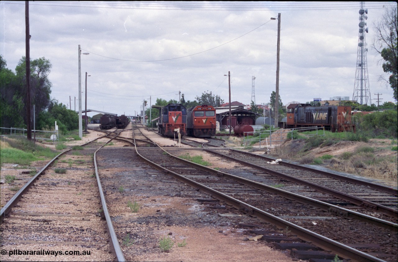 132-20
Mildura station yard overview, Freightgate in the background, oil pot rakes, mainline, loco depot, fuel point behind V/Line broad gauge X class X 32 Clyde Engineering EMD model G16C serial 66-485, G class G 512 Clyde Engineering EMD model JT26C-2SS serial 84-1240, carriage shed, Y class Y 165 Clyde Engineering EMD model G6B serial 68-585.
