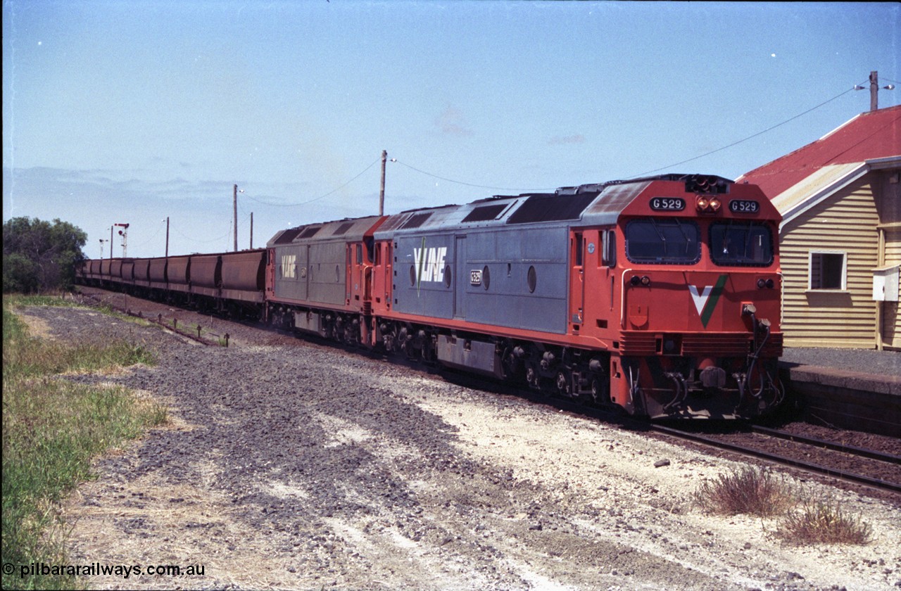 133-18
Gheringhap station building, V/Line broad gauge grain train 9121 heading to Ballarat and beyond, G class G 529 Clyde Engineering EMD model JT26C-2SS serial 88-1259 and G 511 serial 84-1239 pause to exchange electric staves, safeworking, from former No.2 platform.
Keywords: G-class;G529;Clyde-Engineering-Somerton-Victoria;EMD;JT26C-2SS;88-1259;