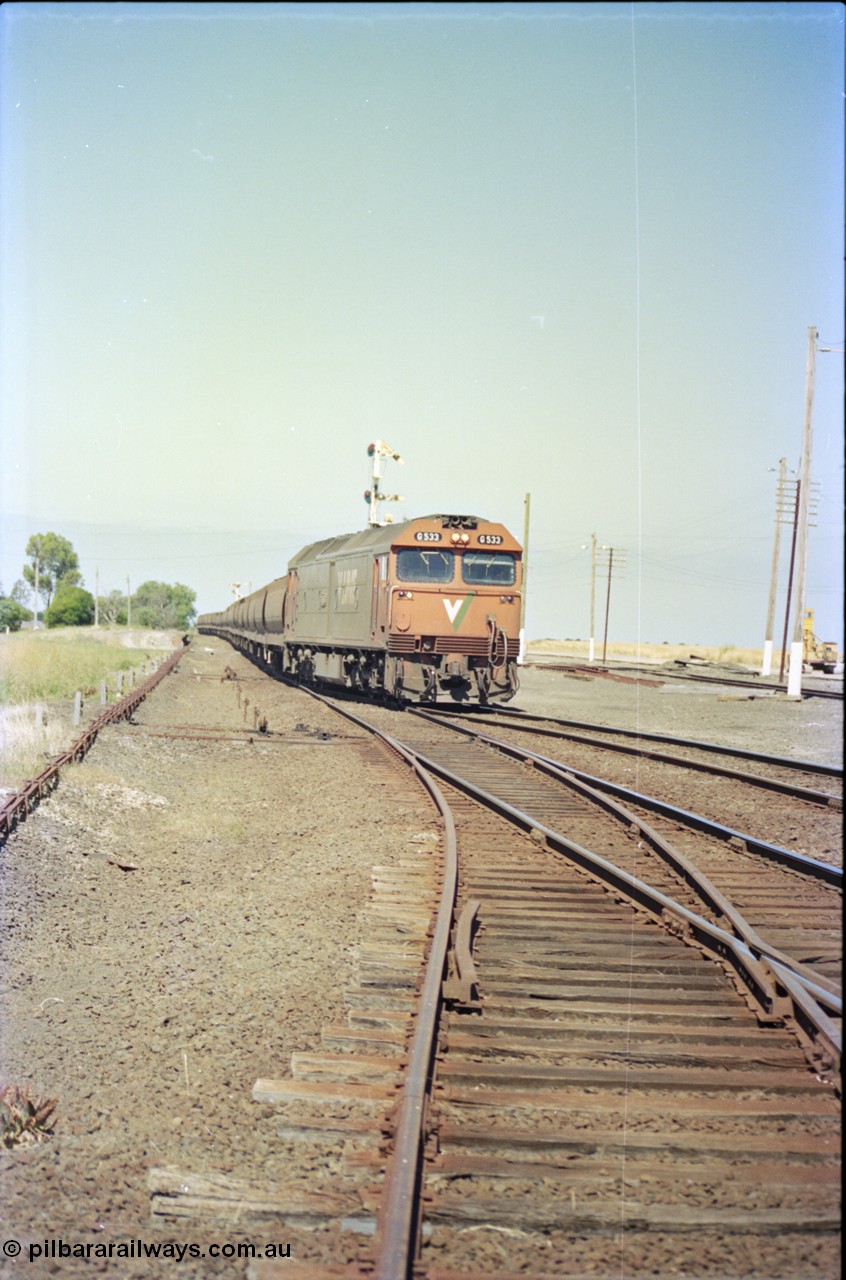 133-34
Gheringhap station yard overview, looking from Ballarat line points, semaphore signal post 4 pulled off for Cressy line, points, point rodding, signal wires and interlocking, V/Line broad gauge down empty grain train 9123 behind G class loco G 533 Clyde Engineering EMD model JT26C-2SS serial 88-1263 onto the Cressy line.
Keywords: G-class;G533;Clyde-Engineering-Somerton-Victoria;EMD;JT26C-2SS;88-1263;