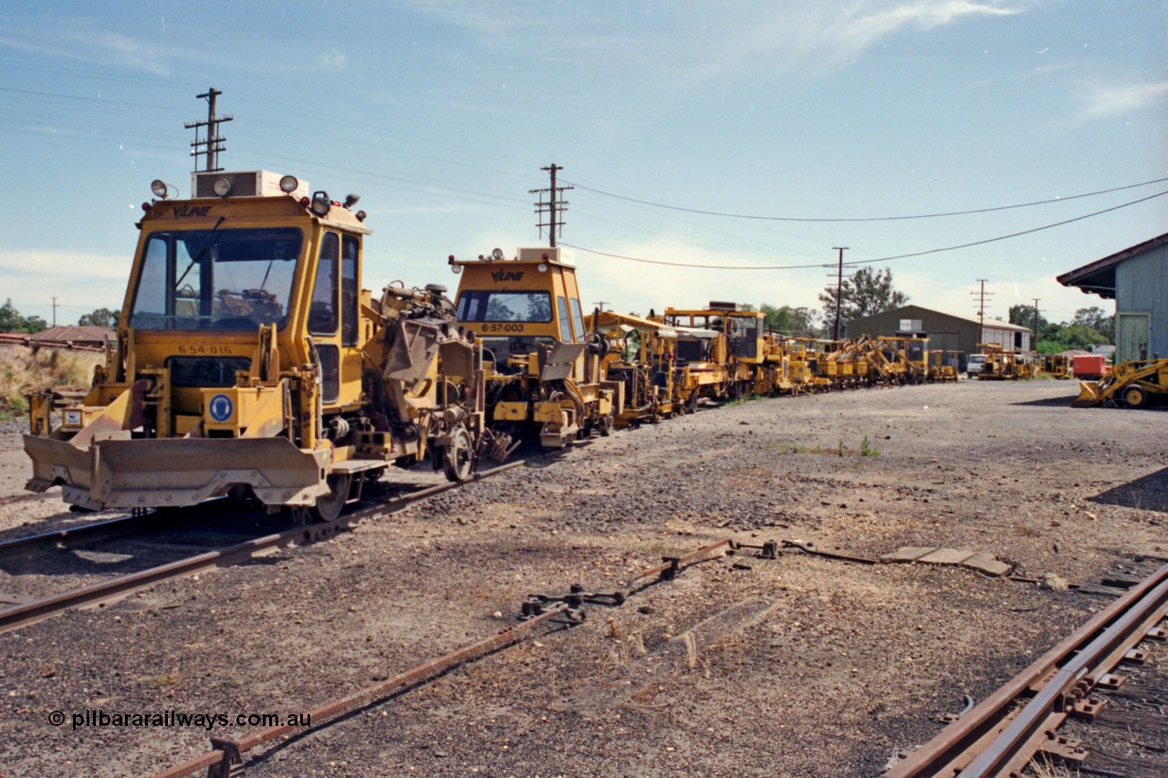 137-1-13
Euroa, V/Line broad gauge track re-surfacing gang's tack machines are stabled on No.5 Rd, ballast regulators, tampers and sleeper inserting machines make up this motley collection, the goods shed is at right of frame.
