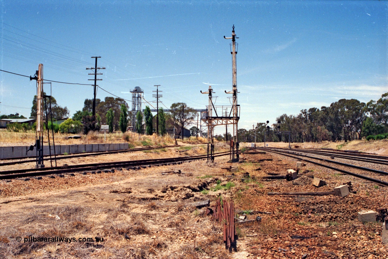 137-1-21
Glenrowan looking north, with all the interlocking having been decommissioned some moths ago, the platform road has been removed, with just the mainline and standard gauge loop remaining. From the far right of the image is the standard gauge loop, then the broad gauge mainline. From where the image was shot is the platform or No.2 Rd, with the goods loop at left with the siding leading up the embankment to the former stock race, now a grain receival site. The remains of disc signal post 8 and semaphore post 7 (with co-acting arms) and a pile of point rodding are in the middle of frame.
