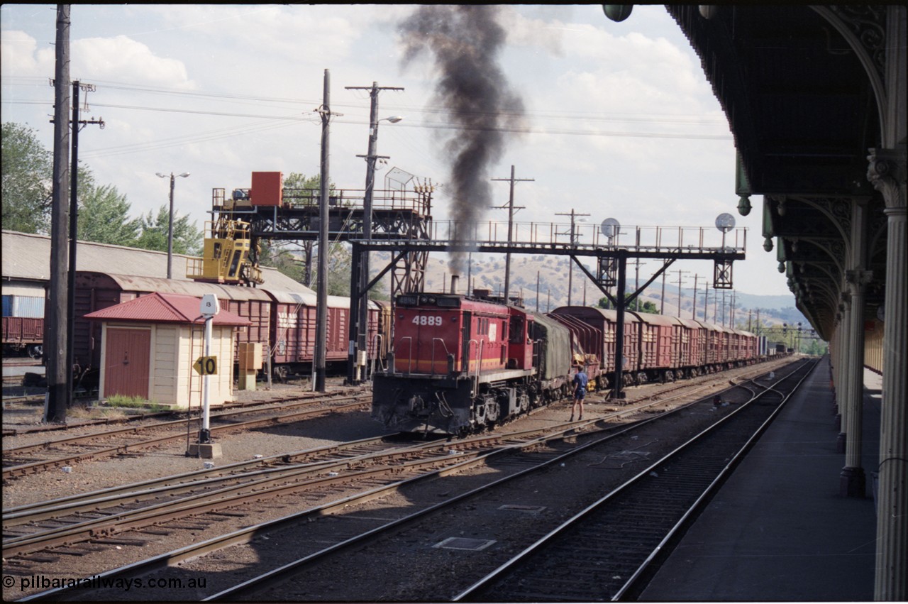 137-2-11
Albury station yard overview, standard gauge NSWSRA candy liveried 48 class 4889 AE Goodwin ALCo model DL531 serial G3420-4 shunts an arrival from Melbourne, the broad gauge 'trans-shipping yard' is to the left of the louvre vans, and a broad gauge track is directly to the left of the loco, ALCo smoke, signal gantry, station platform, shunter on ground.
Keywords: 48-class;4889;AE-Goodwin;ALCo;RSD-8;DL531;G3420-4;