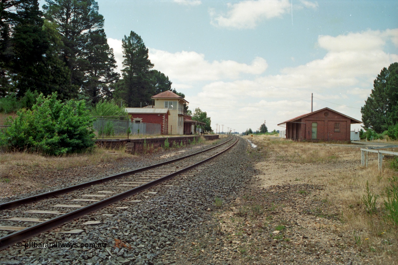 139-02
Creswick station yard overview, gang camp ATCO dongas, siding visible in the grass with baulk, brick goods shed, looking south from the north end, elevated signal box.
